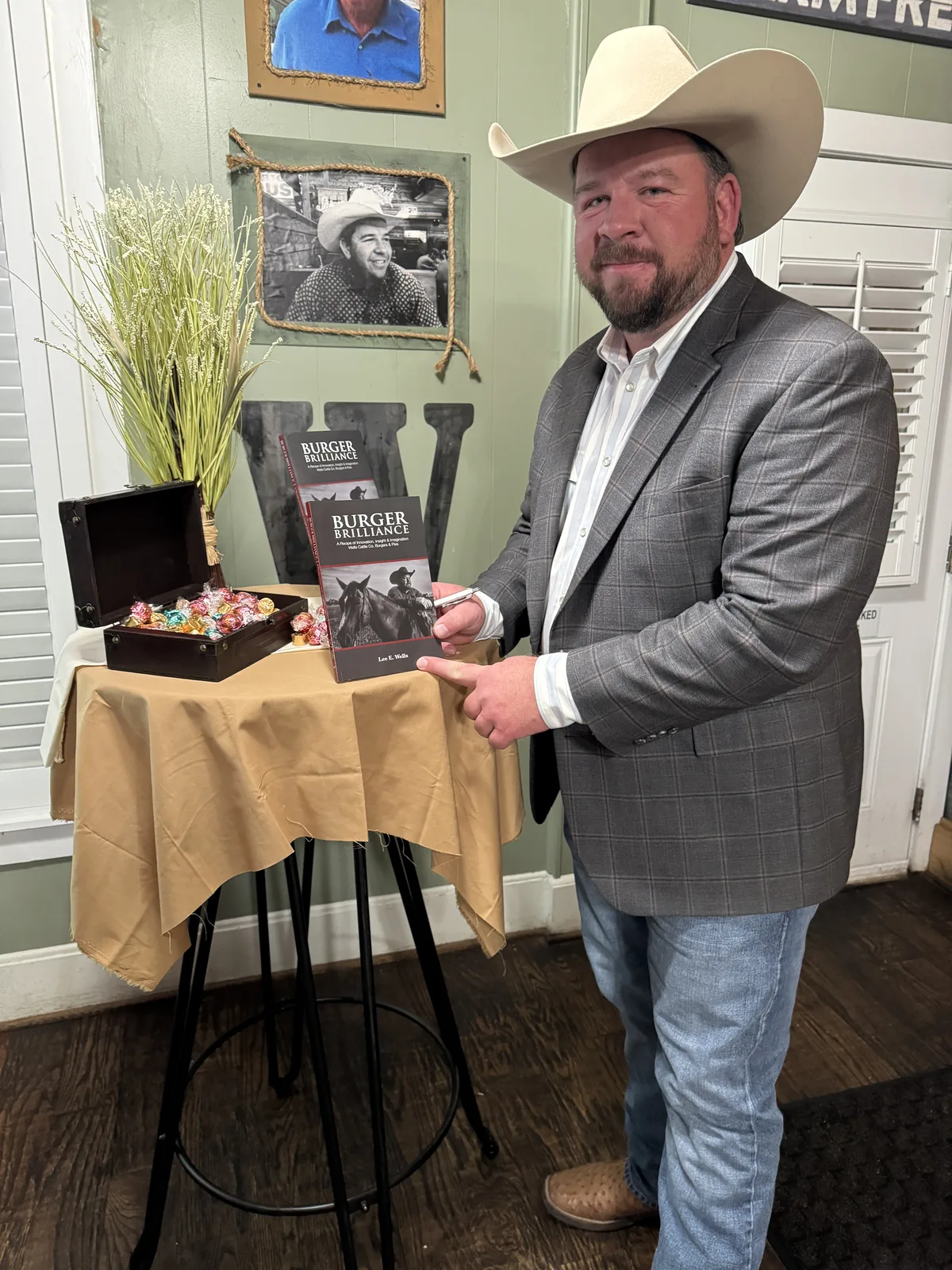 Lee Wells holding a copy of Burger Brilliance in the Rockwall dining room