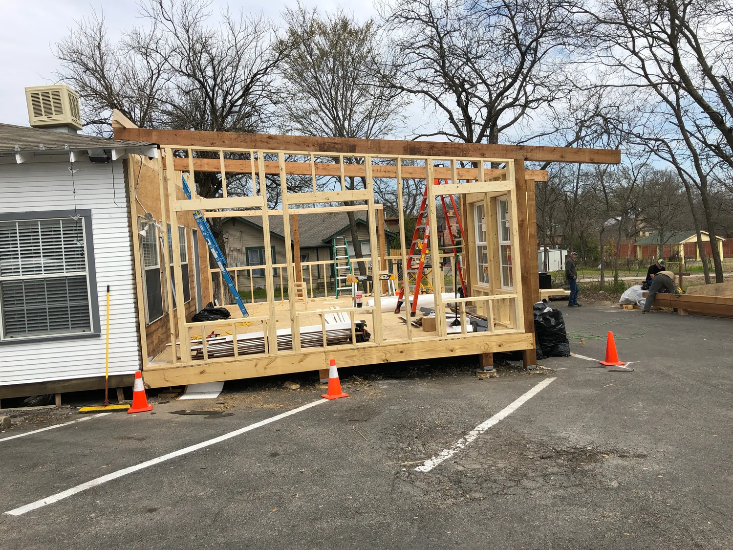 The rear expansion under construction — bare stud framing going up behind the house